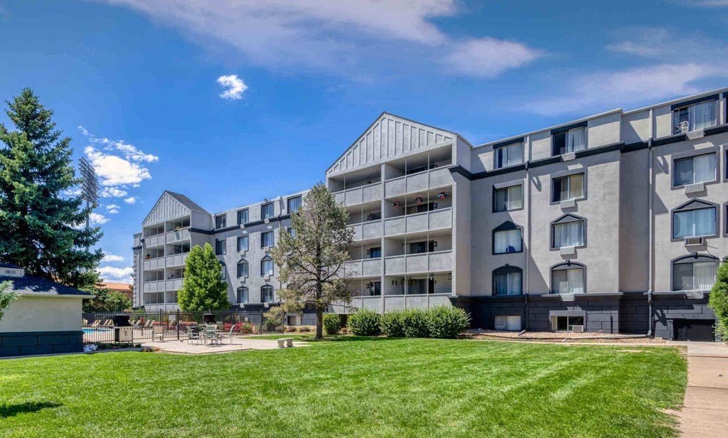 an apartment building with a green lawn in front of it