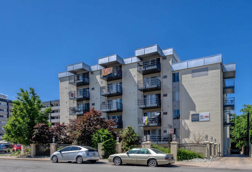 Two cars are parked in front of a large apartment building  at 4805 E Kentucky in Denver, CO