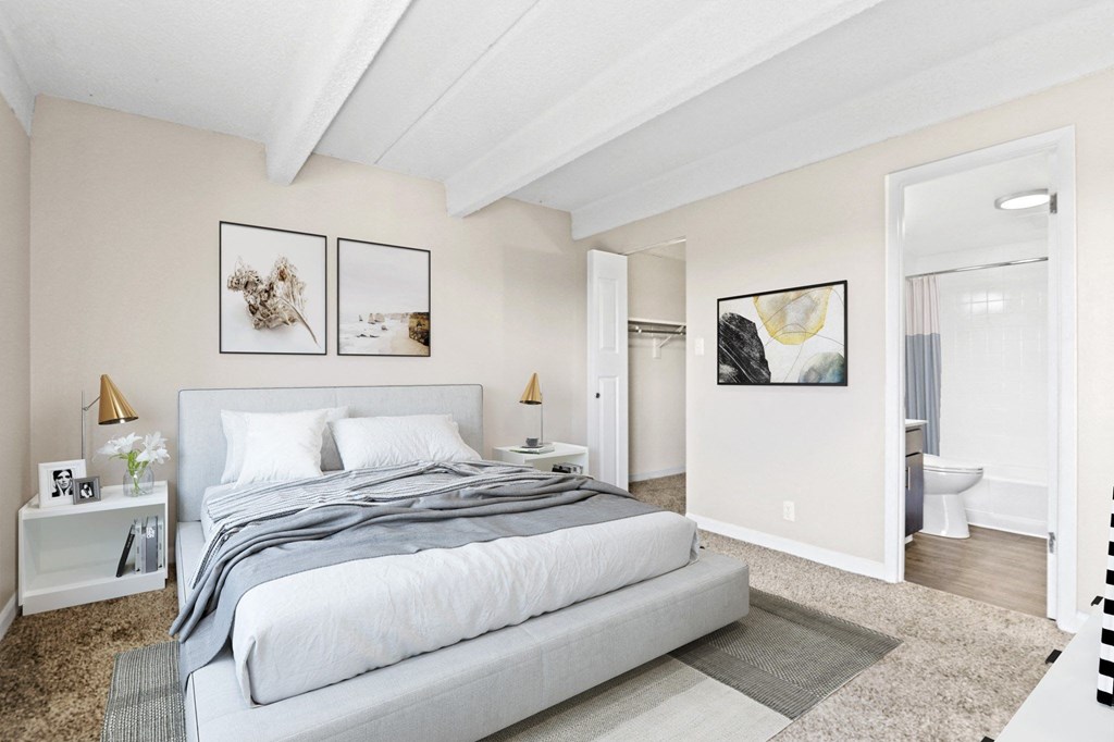 A bedroom with a large bed and two framed pictures on the wall.