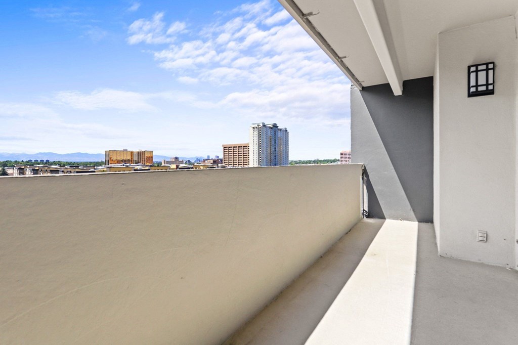 A balcony with a white door and a view of buildings in the distance.
