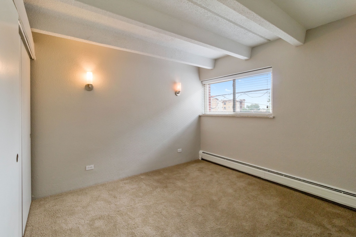 the living room of an apartment with carpet and a window