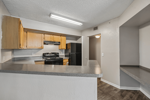 A kitchen with a stove top oven and wooden cabinets.