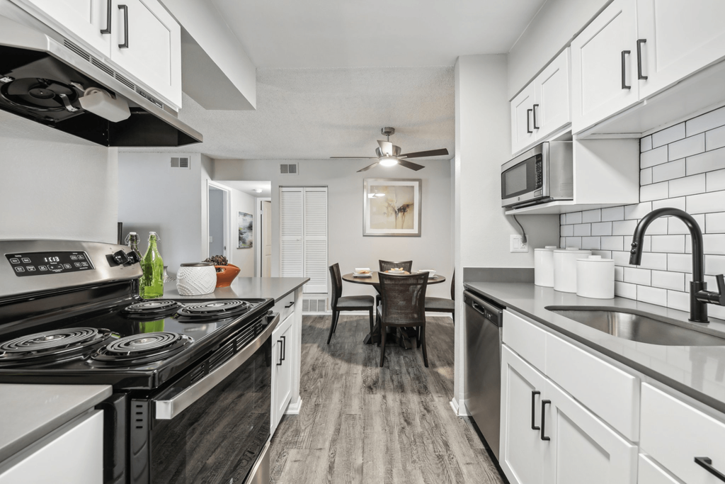 A modern kitchen with a black stove top and white cabinets.