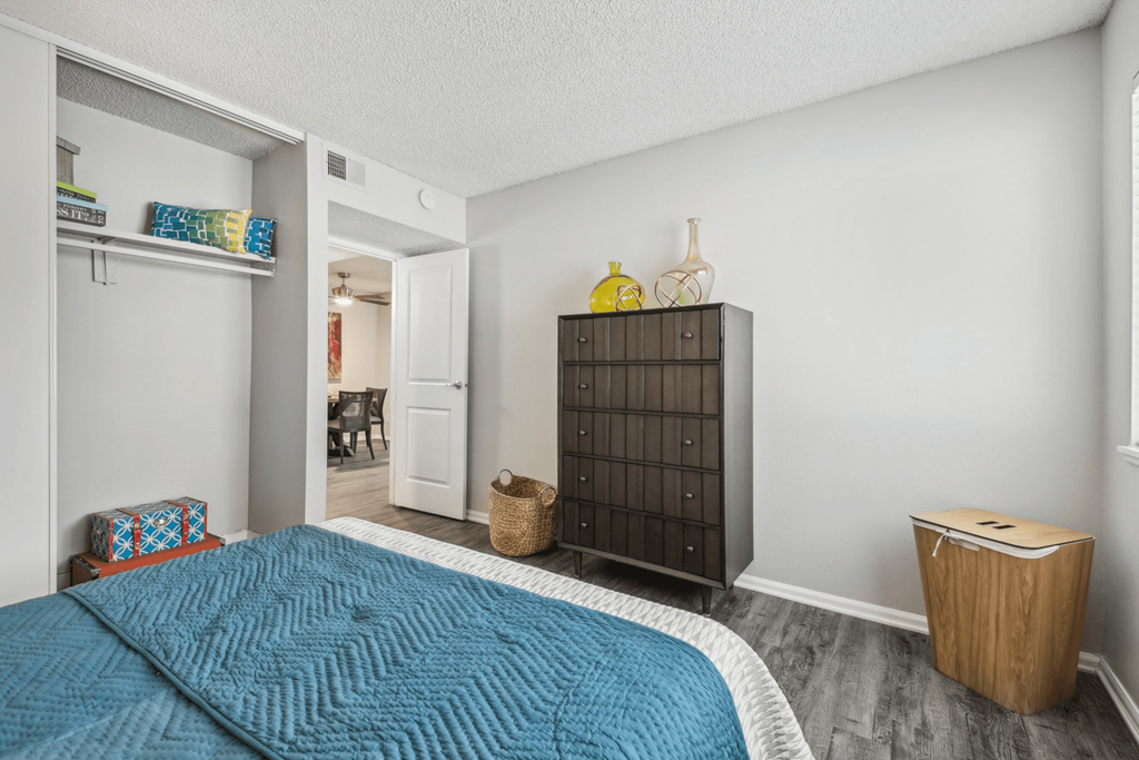 a bedroom with a blue bed and a wooden dresser