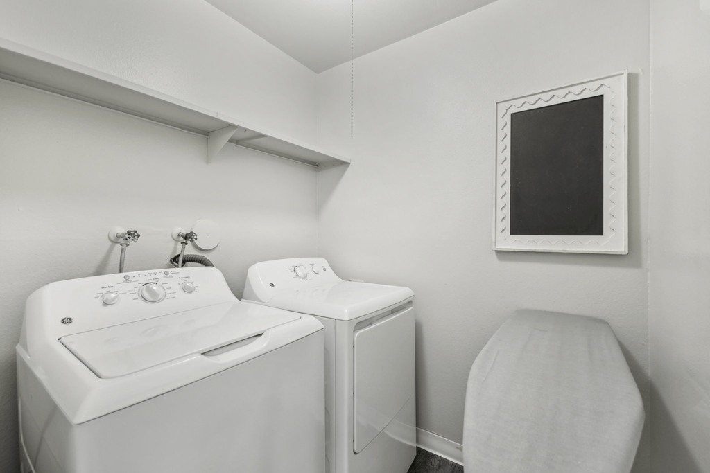 a white washer and dryer in a white laundry room with a white sink