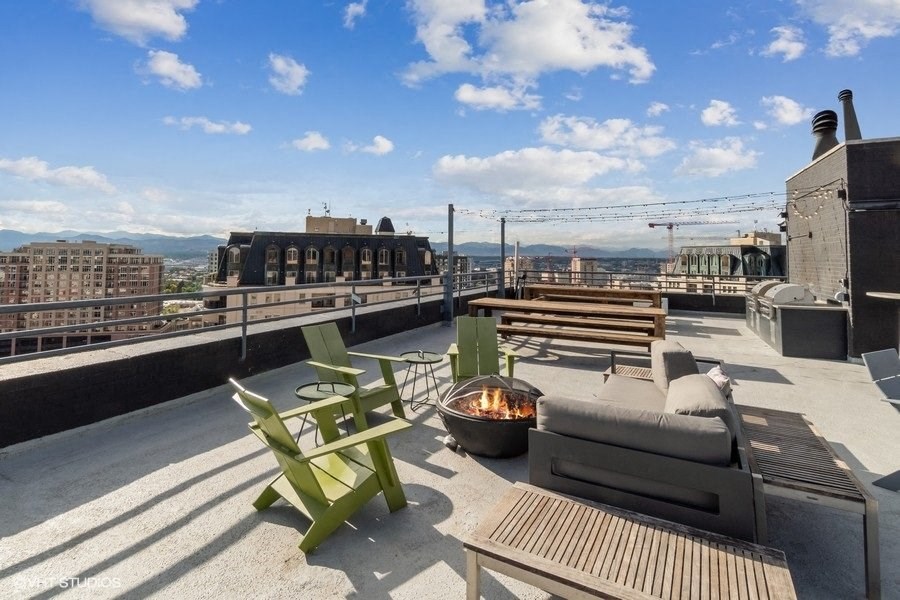 the top of a roof top patio with furniture and a fire pit