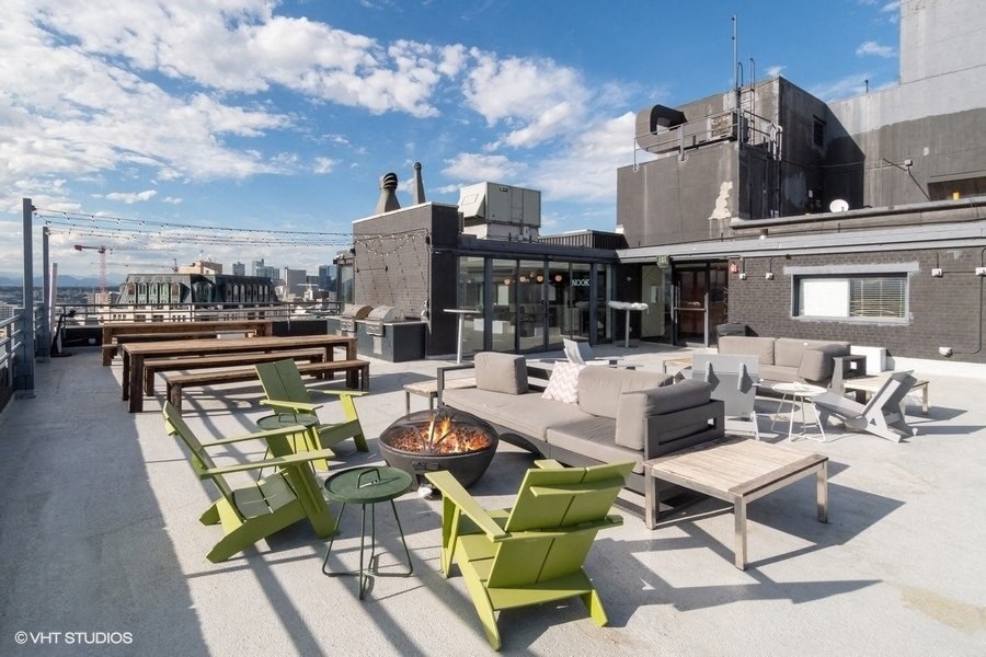 a rooftop patio with furniture and a fire pit on a roof