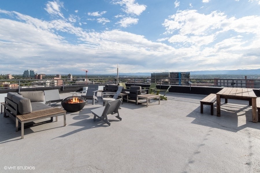 a roof top patio with furniture and a fire pit