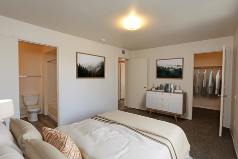 A bedroom with a bed, a cabinet, and two pictures on the wall.