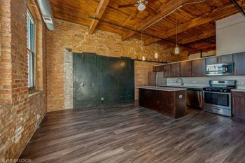 an empty kitchen with brick walls and wood floors