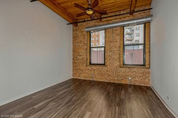 an empty living room with brick and wood floors and a ceiling fan