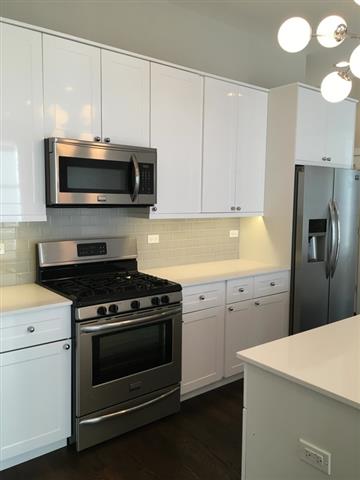 A modern kitchen with white cabinets and stainless steel appliances.