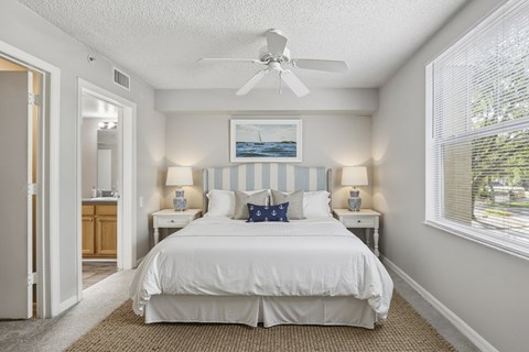 A bedroom with a white bed and a ceiling fan.