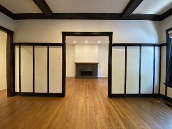 A room with wooden floors and a fireplace with a black frame.