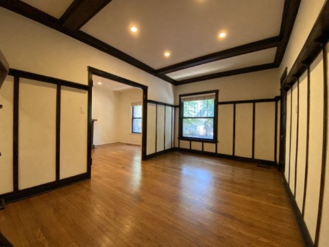 a living room with wooden floors and white walls and a window