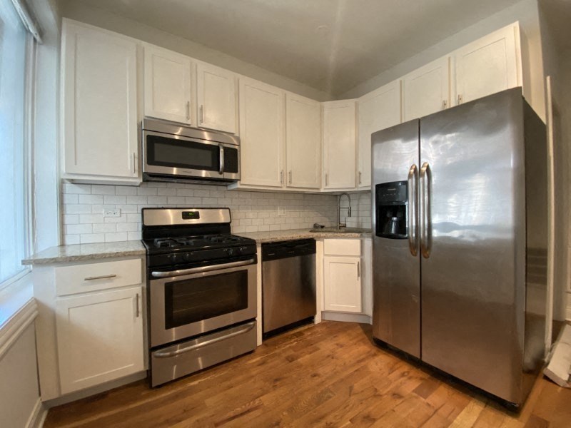 Spacious kitchen space with hardwood floors and stainless steel appliances
