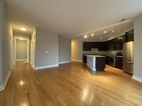 A kitchen with a stainless steel refrigerator and wooden floors.