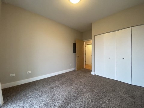 an empty living room with carpet and white cabinets