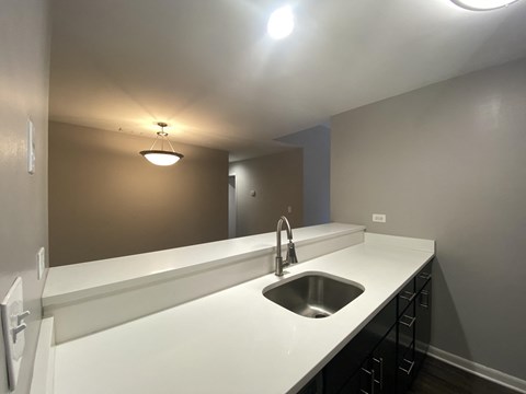 an empty kitchen with a sink and a mirror