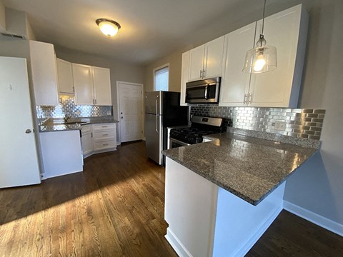 A kitchen with a granite countertop and stainless steel appliances.