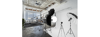 A photography studio with a ceiling fan, lighting equipment, and a couch.