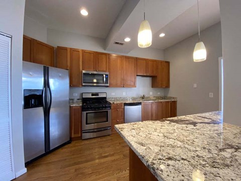 A kitchen with a granite counter top and wooden cabinets.