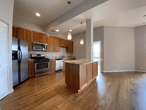 an empty kitchen with wood floors and stainless steel appliances