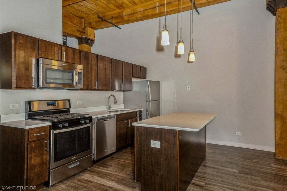 Kitchen with rich wood cabinetry and stainless steel appliances at Carriage House Lofts, Chicago, 60605