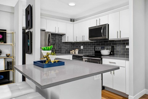 Modern kitchen with white cabinets and gray subway tile backsplash at Eleven Thirty Apartments, Chicago, IL 60605