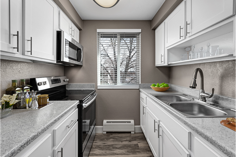 a kitchen with white cabinets and a sink and a window