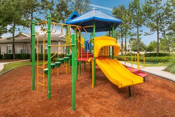 A playground with a yellow slide and green and yellow play equipment.