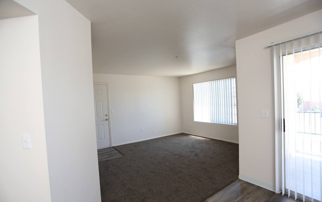 Large living room with bright natural light and plush carpeting at Canon de Arrowhead in Albuquerque, New Mexico