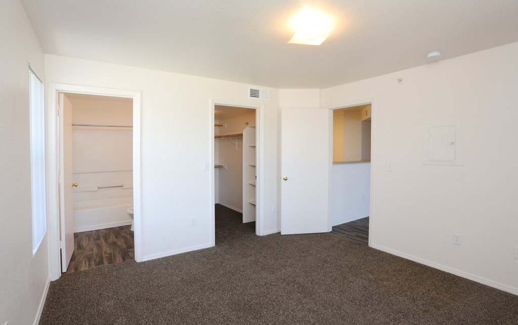 Bedroom with plush carpeting and a private bathroom at Canon de Arrowhead in Albuquerque, New Mexico