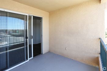 A balcony with a sliding glass door and a beige wall.