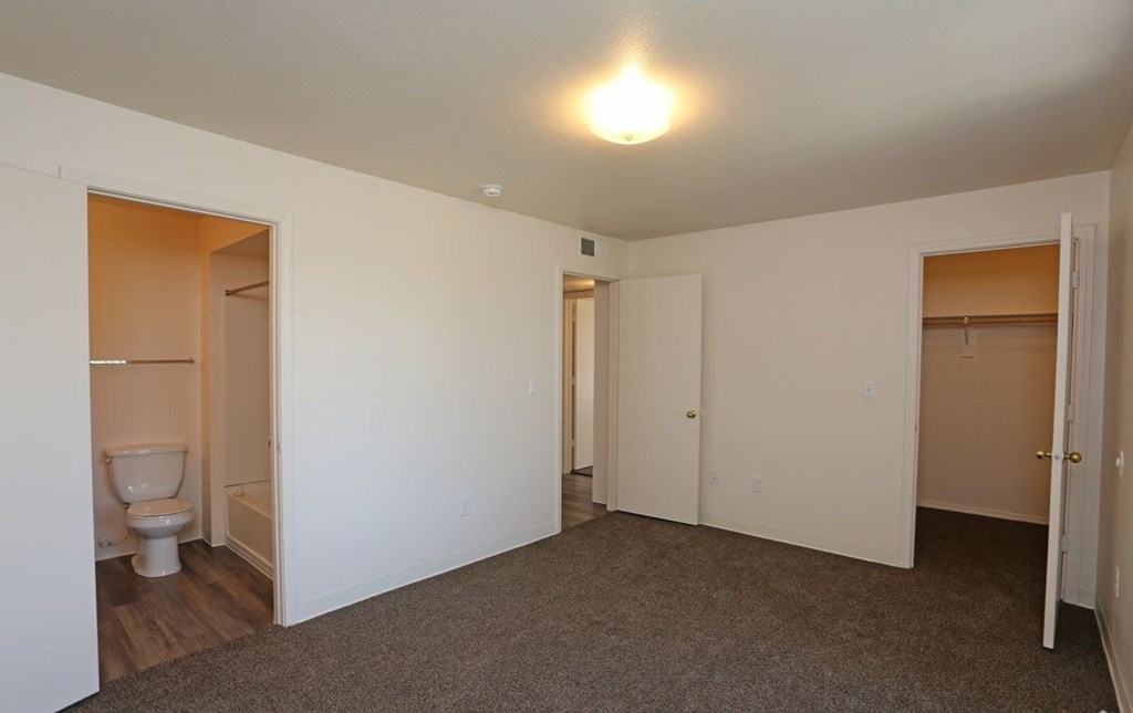 Bedroom with plush carpeting and a private bathroom at Canon de Arrowhead in Albuquerque, New Mexico