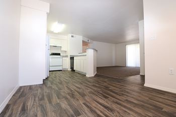 A kitchen with white appliances and a brown floor.