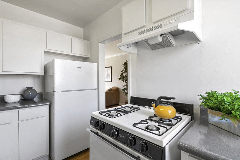 a white kitchen with a stove and a yellow kettle