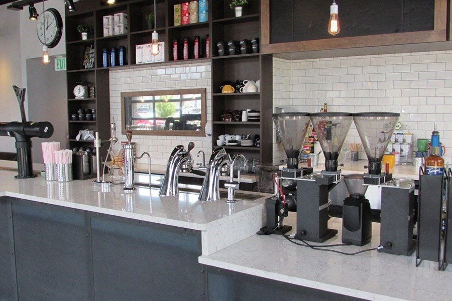 A bar with a coffee machine and a shelf with bottles at Wash Park Station in Denver, CO