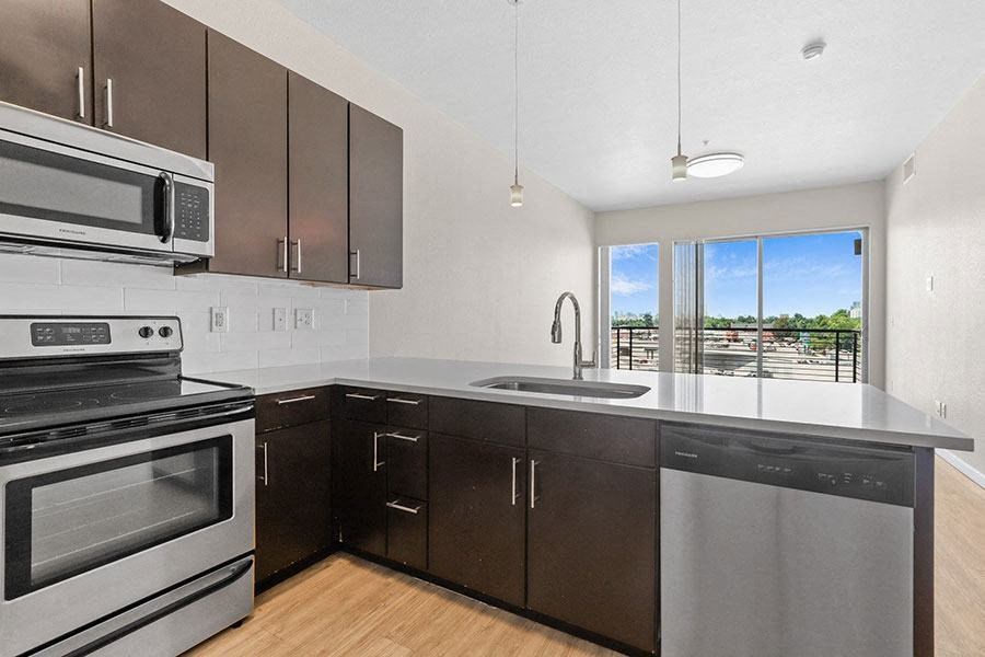 A kitchen with dark brown cabinets and stainless steel appliances at Wash Park Station in Denver, CO