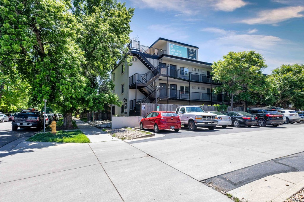 the view of an apartment building with cars parked on the street