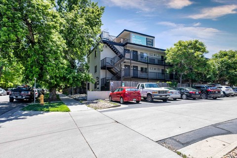Full view of modern apartment complex with tree-lined street, parking area, and updated exterior design at 1443 Elizabeth in Denver, CO