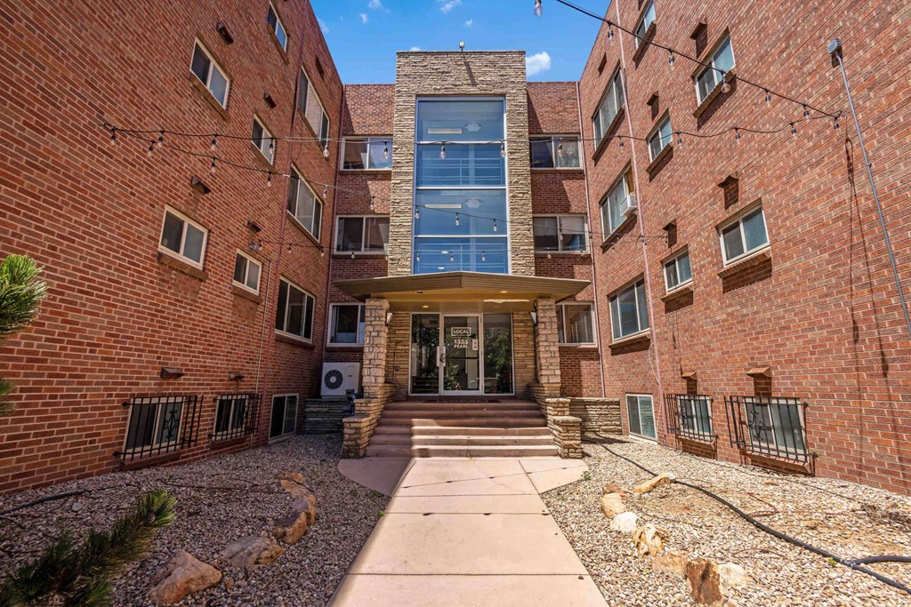 A brick building with a glass entrance and a stone pathway leading to it.