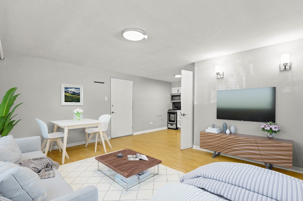A modern living room with a grey sofa, a wooden coffee table, a flat-screen TV, and a kitchen area in the background at 1355 Pearl in Denver, CO