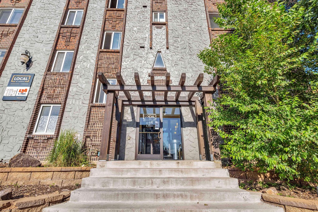 the front of a brick building with stairs and a glass door