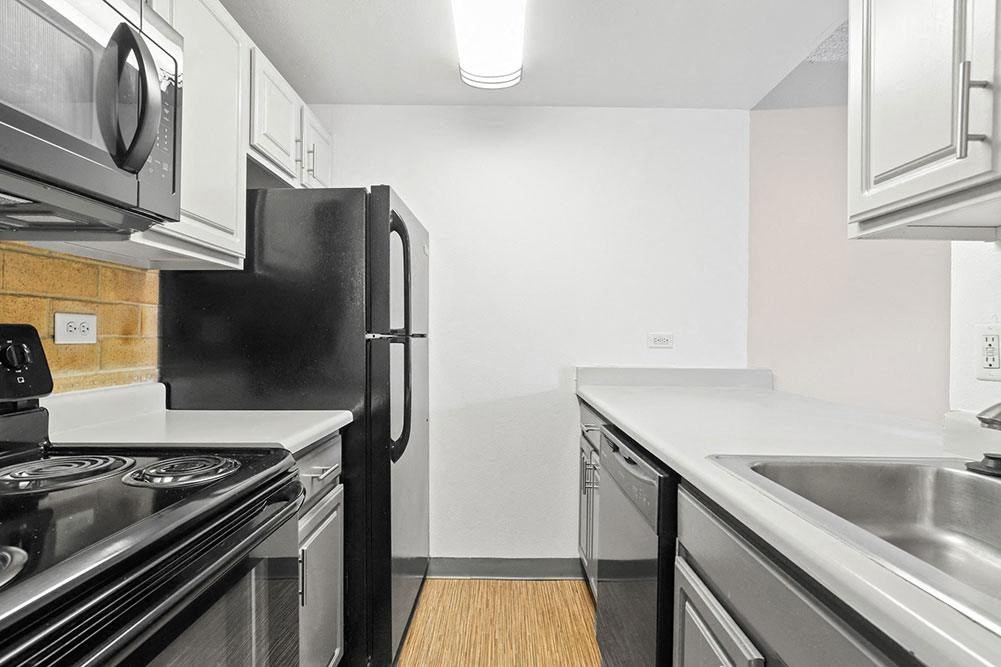 a kitchen with stainless steel appliances and a black refrigerator