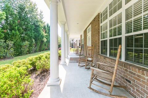 Rocking chairs on a large covered patio for residents to enjoy the peaceful surroundings