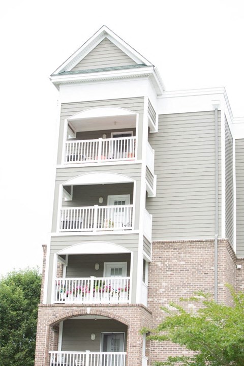 A tall building with a grey facade and white balconies.