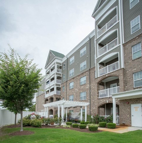 A large apartment complex with a white pergola in the front yard.