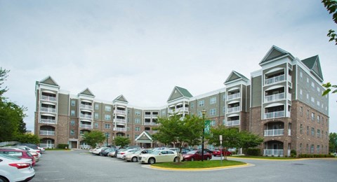 A parking lot in front of a large apartment building.