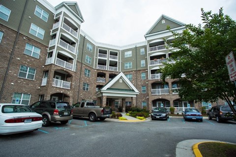 A parking lot in front of a multi-story apartment building.